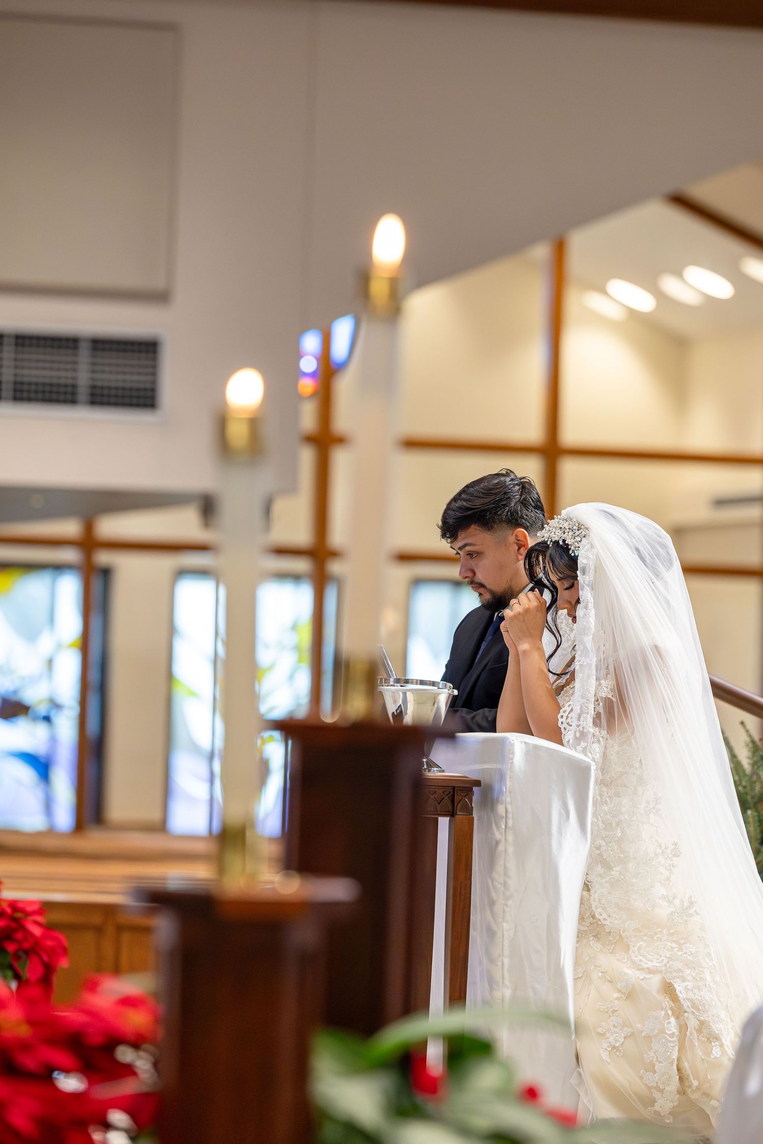 A bride and groom exchange vows in a church sanctuary with wooden pews and warm lighting.