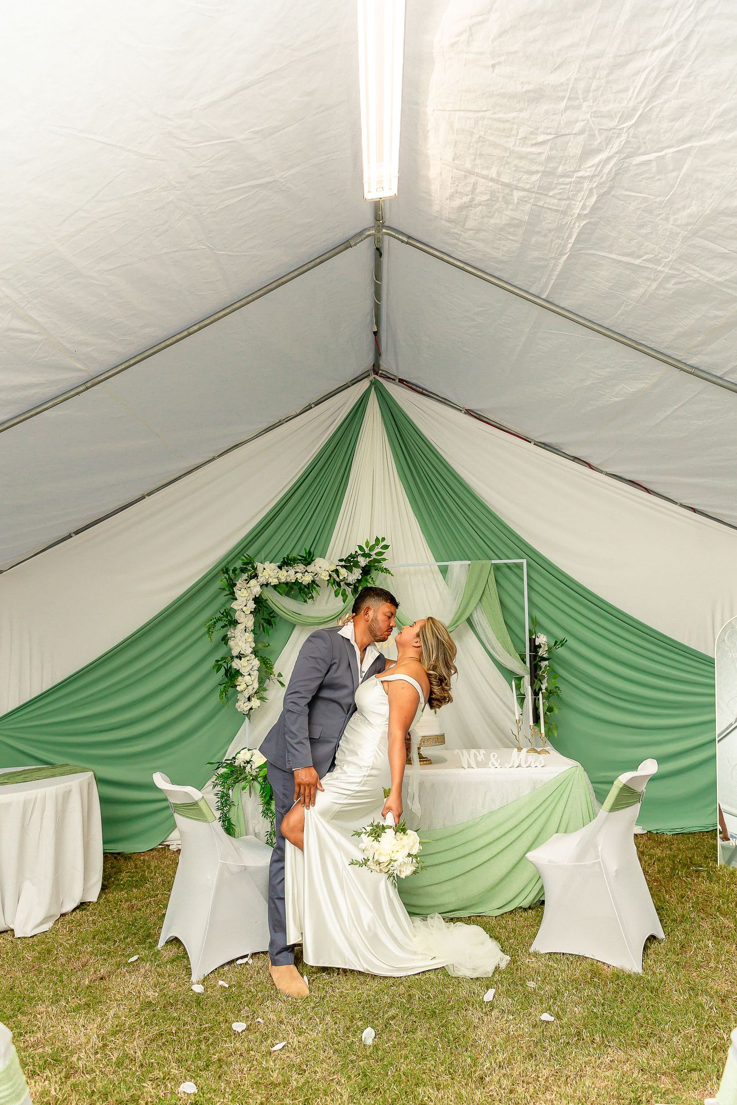A romantic wedding scene with green and white tent draping and floral decorations creates an intimate outdoor setting.