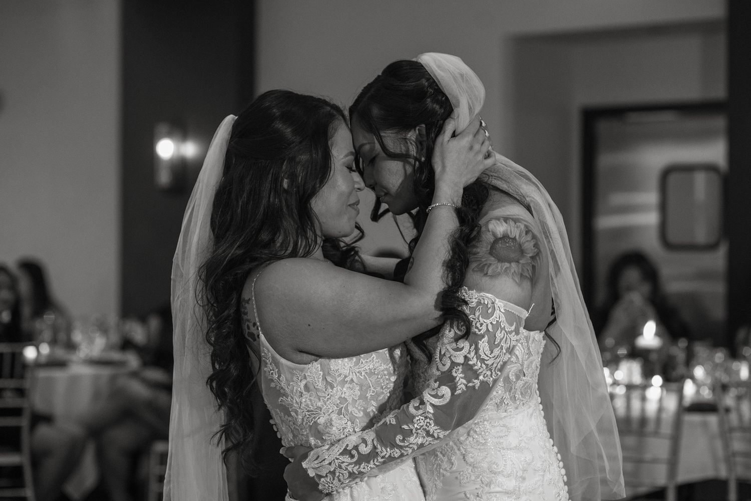 Two brides share their first dance during their wedding celebration in an elegant venue with soft lighting at Tom Ham's Lighthouse.