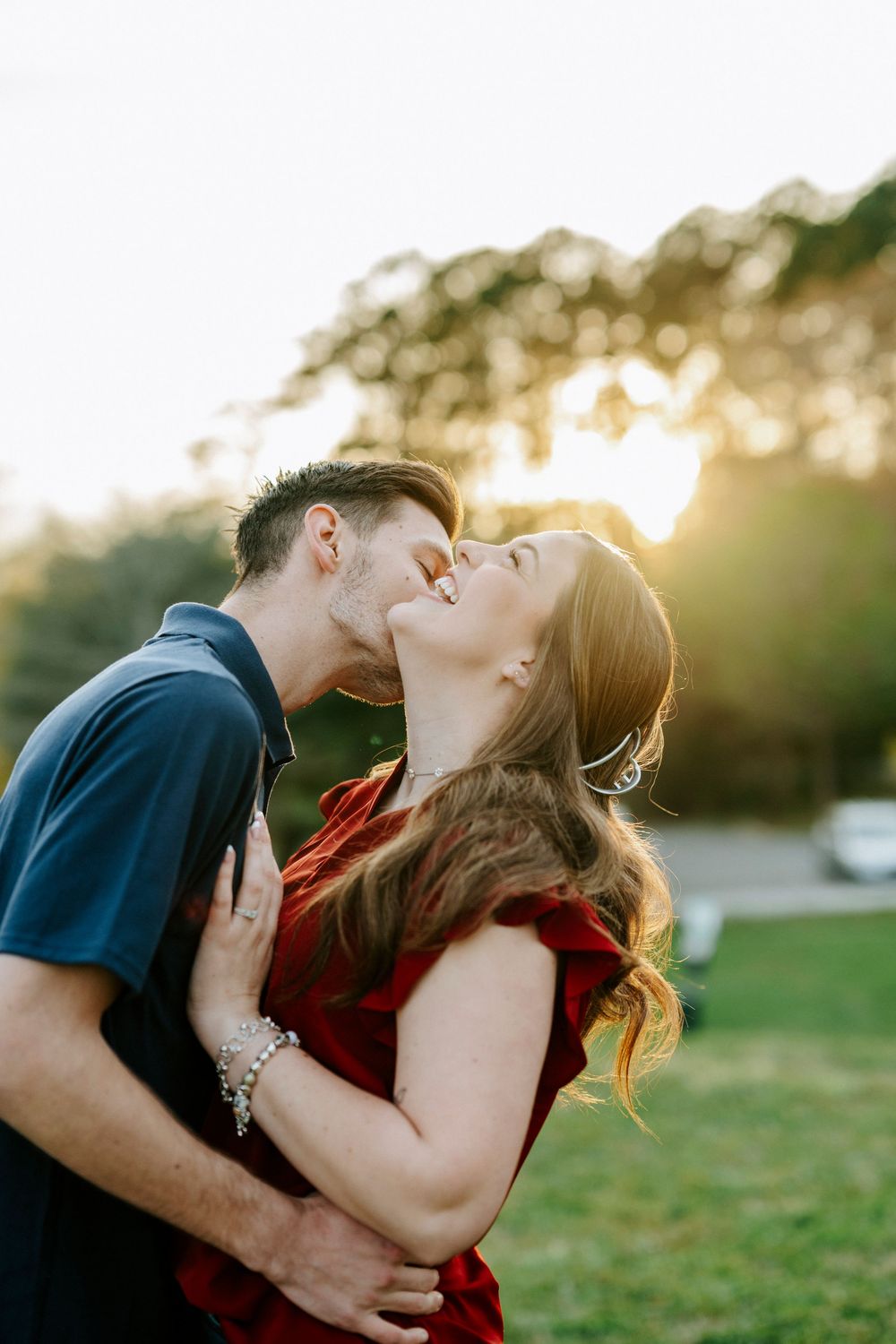 Romantic couple embraces during a golden sunset in a grassy field.
