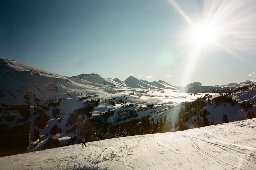 Stunning panoramic view of snow-covered mountains with bright sunlight and blue sky.