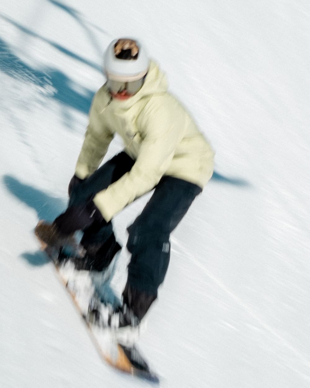 Sequence showing a snowboarder in light-colored gear performing dynamic turns on a snowy slope.