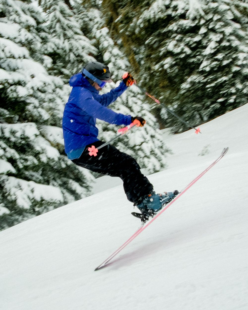 A skier performing an impressive aerial jump sequence in deep powder snow against a backdrop of snow-covered evergreens.
