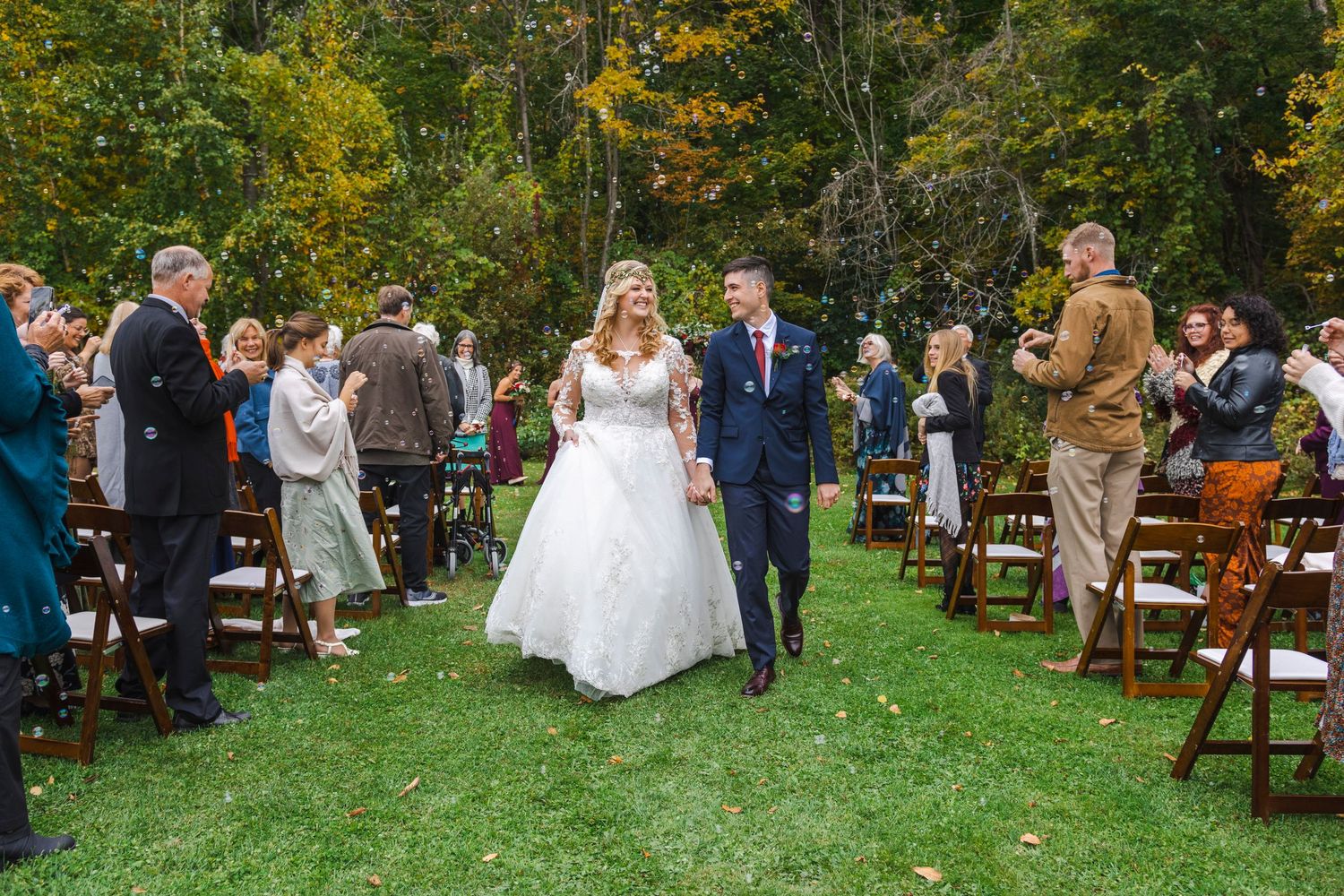 A couple shares intimate moments in a lush green vineyard setting wearing wedding attire and floral crown.