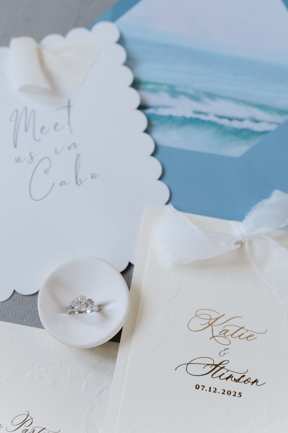 Elegant wedding invitation suite for Katie and Stinton with diamond ring, scalloped cards, and ocean photo in Cabo.