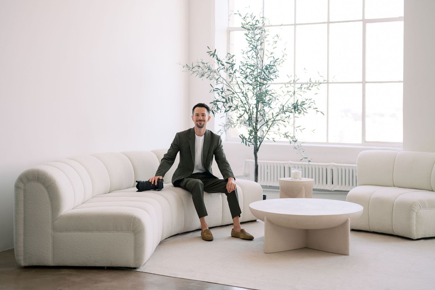 Professional sitting in modern white minimalist office space with clean furniture and natural lighting.