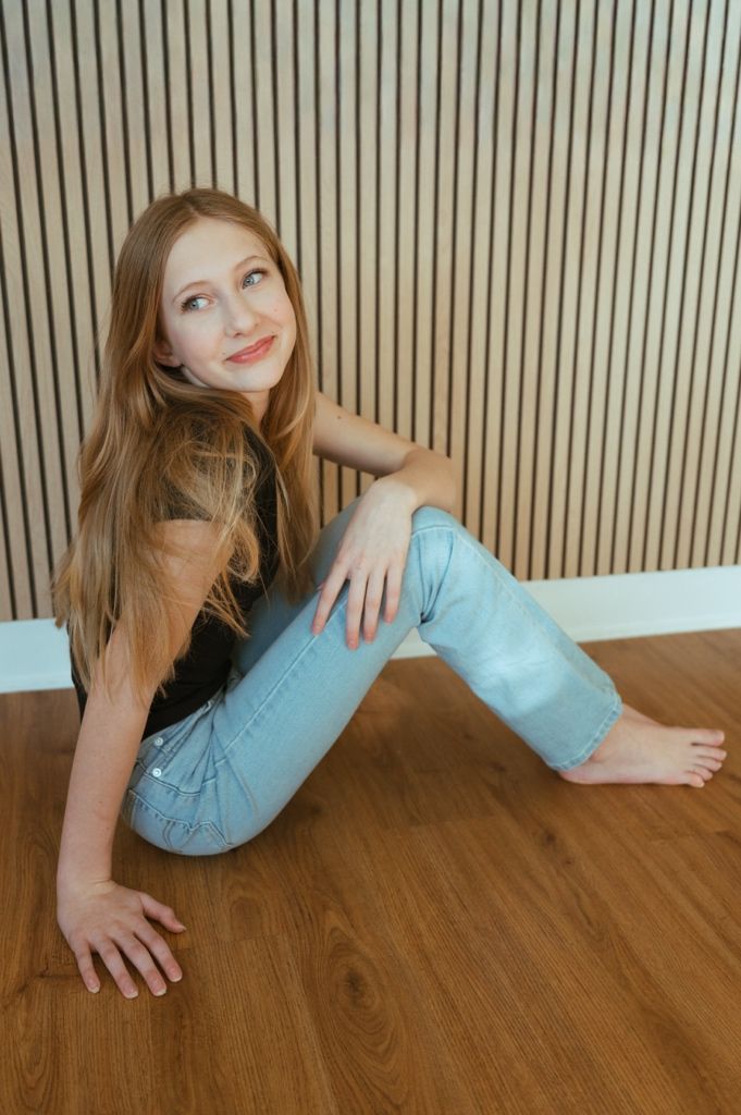 A series of artistic portrait poses showing someone in a light blue top against a striped wall backdrop.
