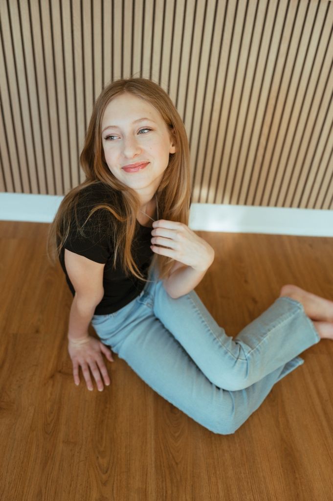 Person in light blue sweater lying on wooden floor with playful expressions in sequence of connected photos.