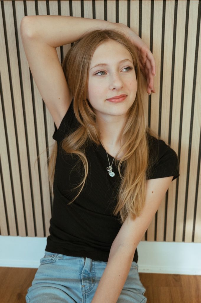 Dynamic fashion poses featuring a black top and blue jeans against vertical striped wallpaper.