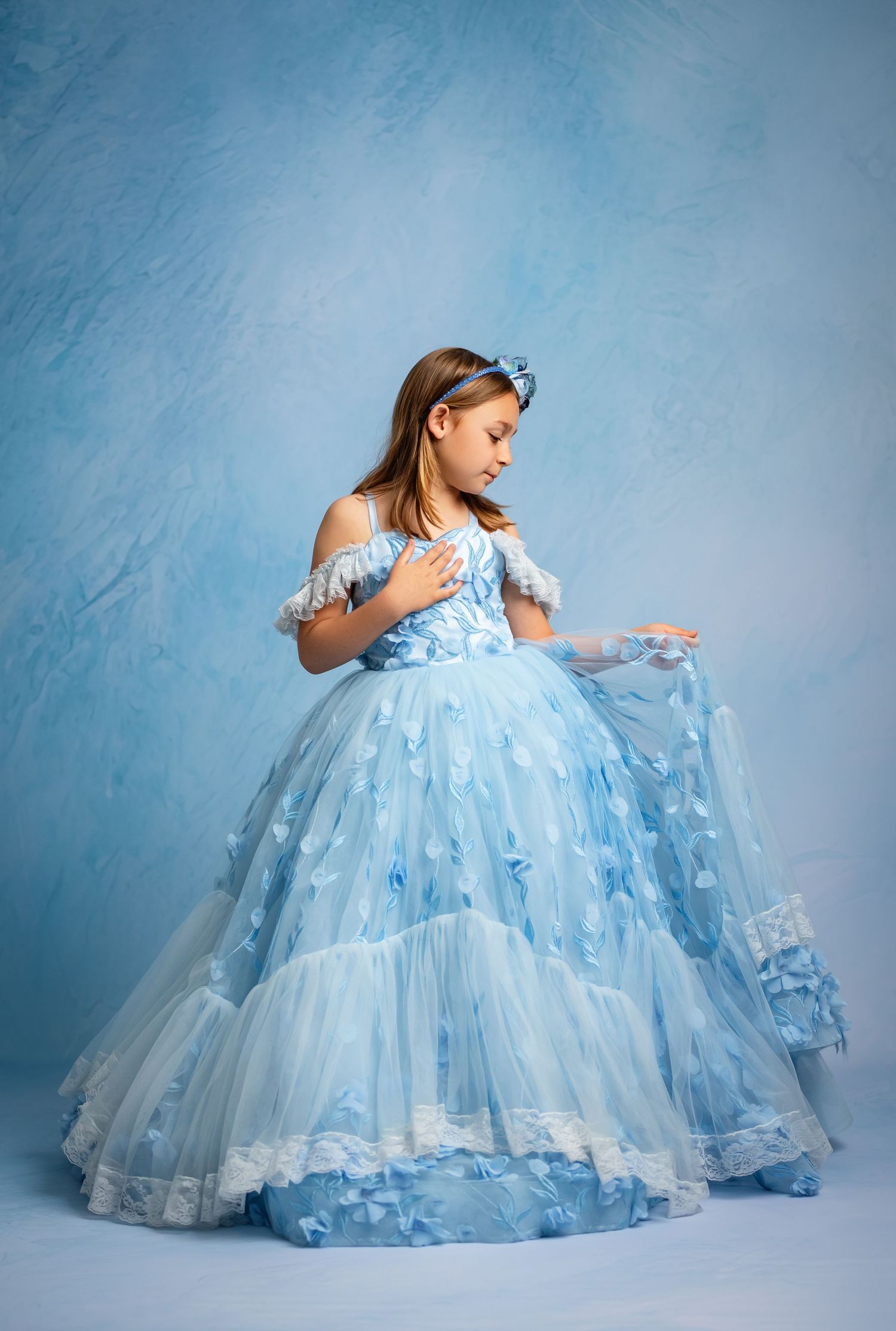 Magical winter portrait in white gown against ice castle backdrop with sparkling snow effects.