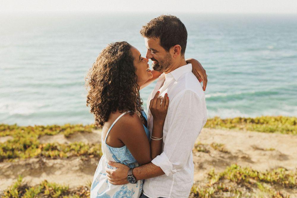 Romantic couple hugging by the ocean during golden hour pre wedding photoshoot in Sesimbra Portugal