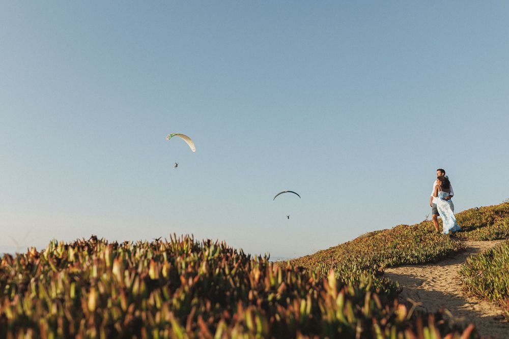 Wide landscape shot of couple walking on cliffs during pre wedding photoshoot in Sesimbra Portugal