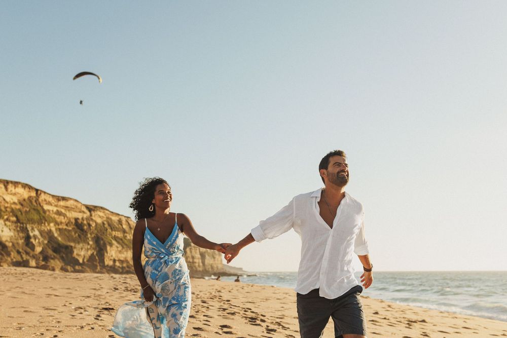 Playful couple running on the beach during pre wedding photoshoot in Sesimbra Lisbon coast