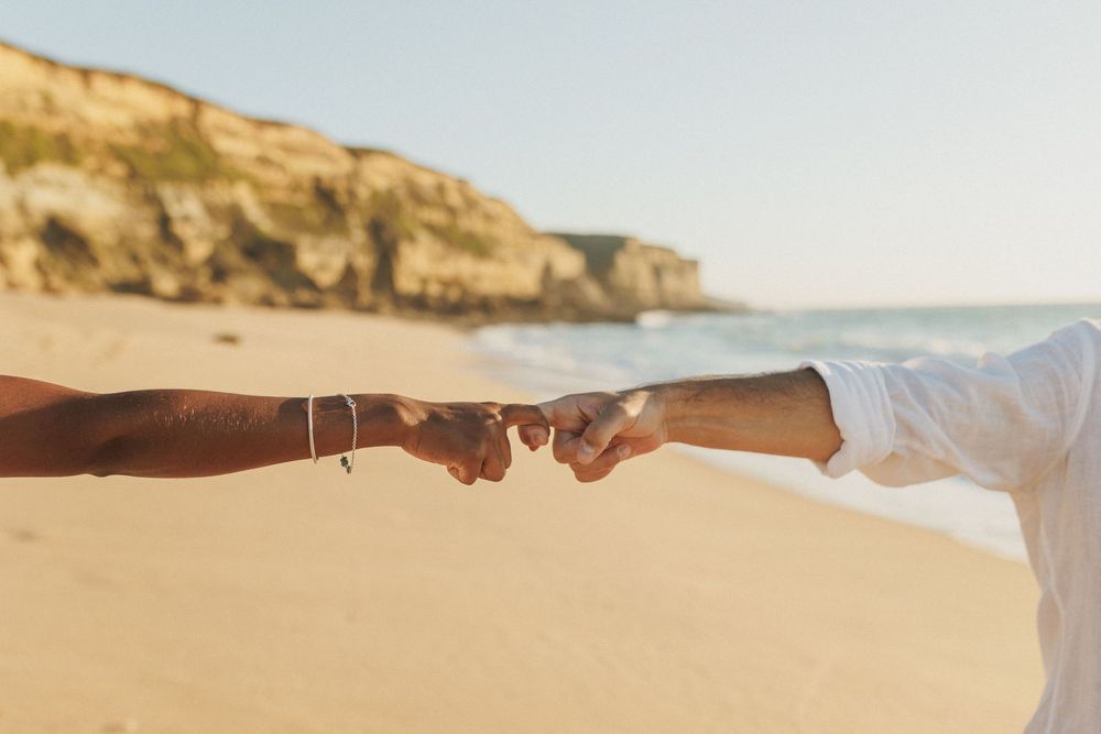 Detail of couple touching hands on the beach during pre wedding session in Sesimbra