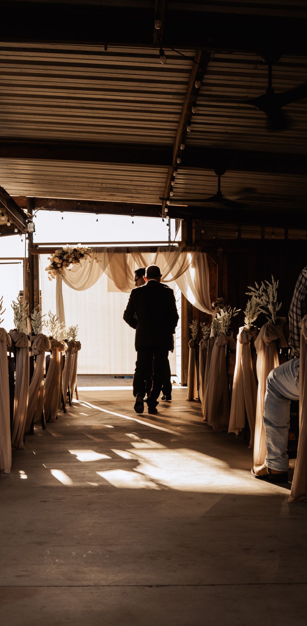 Sunlight streams through curtained windows creating dramatic shadows in an empty industrial warehouse space.