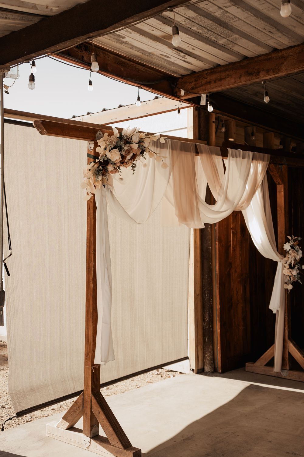 Rustic wooden photography studio setup with white fabric backdrops and natural lighting.