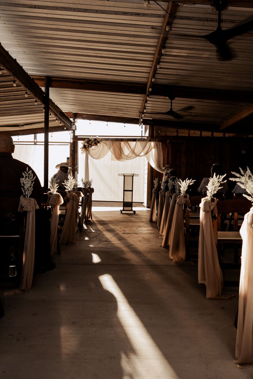 Rustic barn wedding venue interior with draped fabric and natural light streaming through windows.