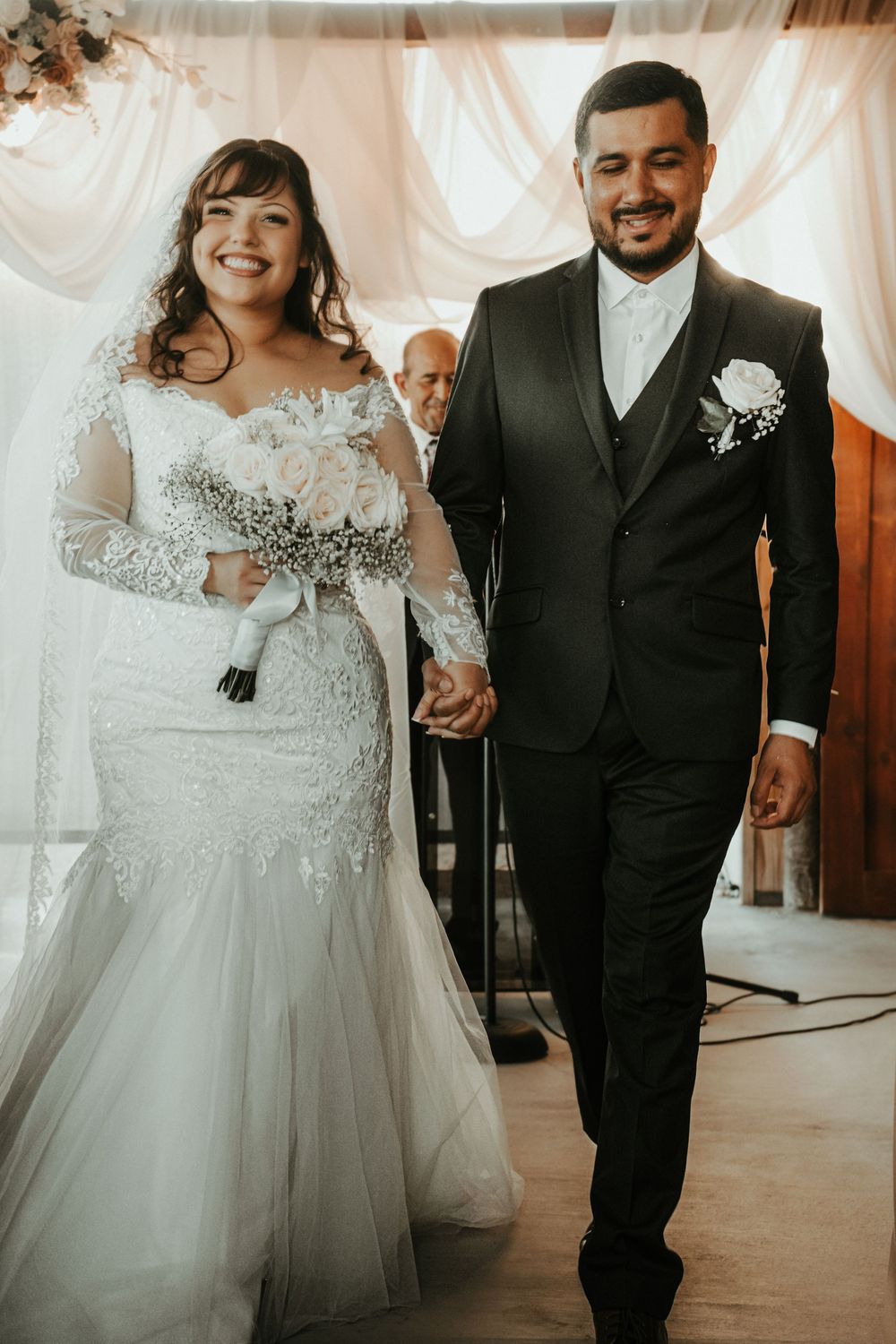 A happy couple at their wedding celebration wearing formal attire and sharing joyful moments together.