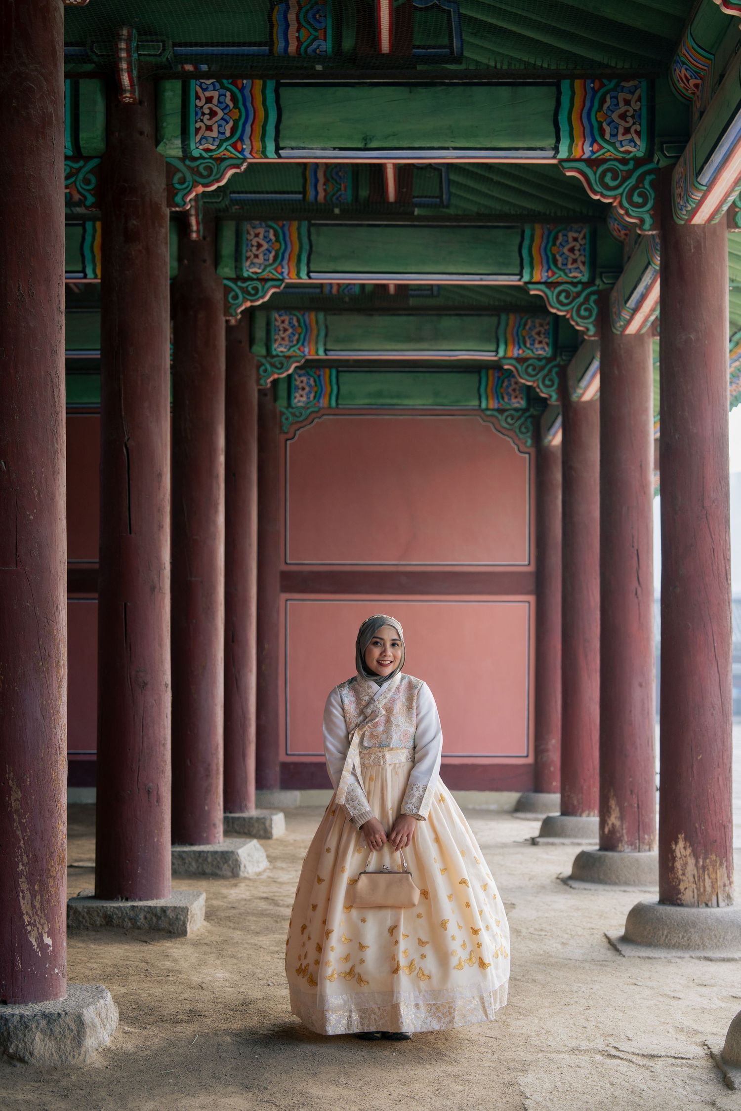 Traditional Korean architecture features wooden columns and ornate green painted details in a historic palace courtyard.