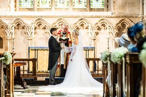 Bride and groom exchange vows at ornate church altar with officiant during elegant wedding ceremony.
