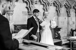 Black and white photo of a bride laughing joyfully with her groom during a church wedding ceremony.