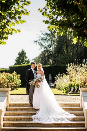 Bride and groom posing on stone steps in a beautiful garden at a stately home wedding.