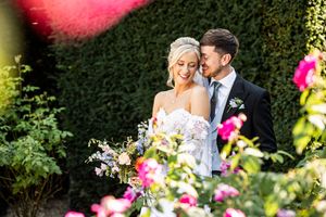 Bride and groom sharing a romantic moment surrounded by colorful flowers in a garden.