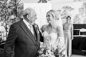Emotional bride sharing a joyful moment with her father before the wedding ceremony, black and white.