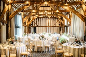 Elegant barn wedding reception with round tables, gold chiavari chairs and fairy lights.