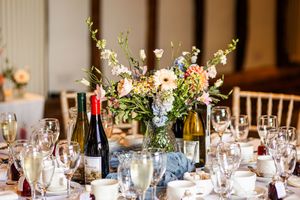Elegant round wedding reception table with floral centerpiece and wine glasses.