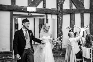 Bride and groom smiling as they exit wedding ceremony in black and white photo.