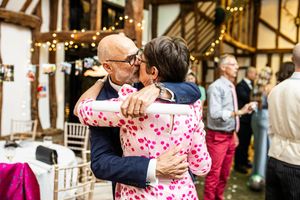 Two wedding guests share a warm embrace on the dance floor at a rustic barn wedding.