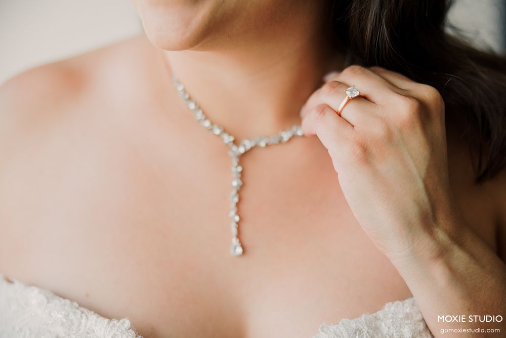 Close-up detail of an elegant crystal drop necklace and white lace wedding dress.