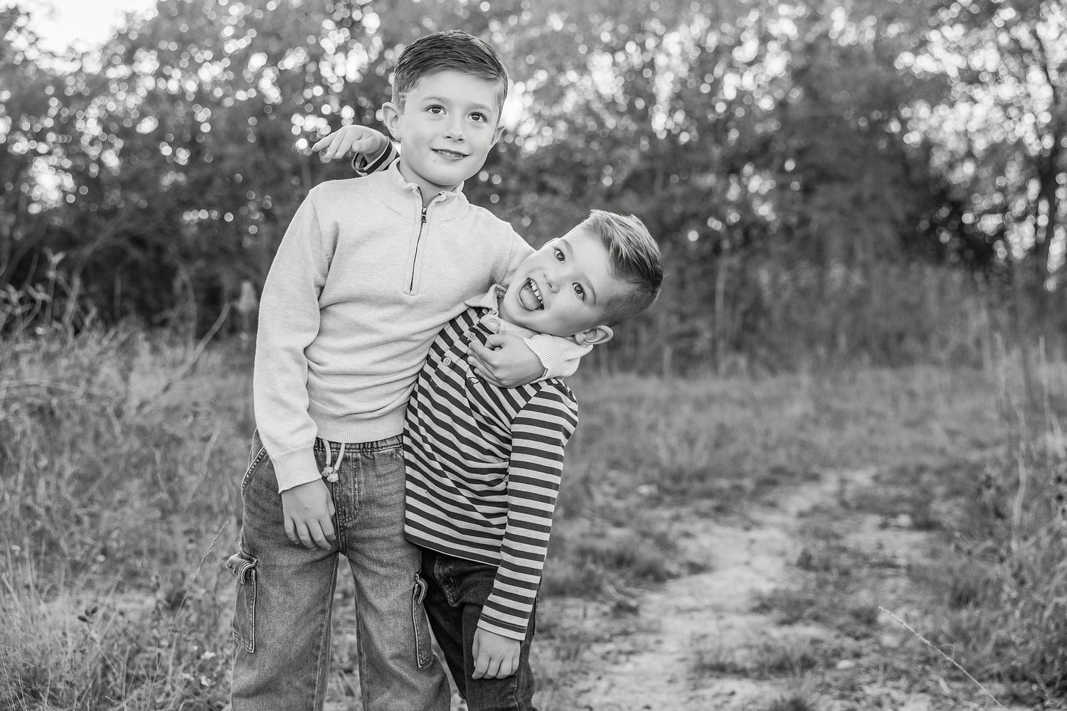 Black and white photos of playful moments between siblings in a natural outdoor setting.
