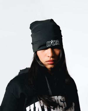 Person wearing a black beanie and dark clothing poses in three different positions against a white background.