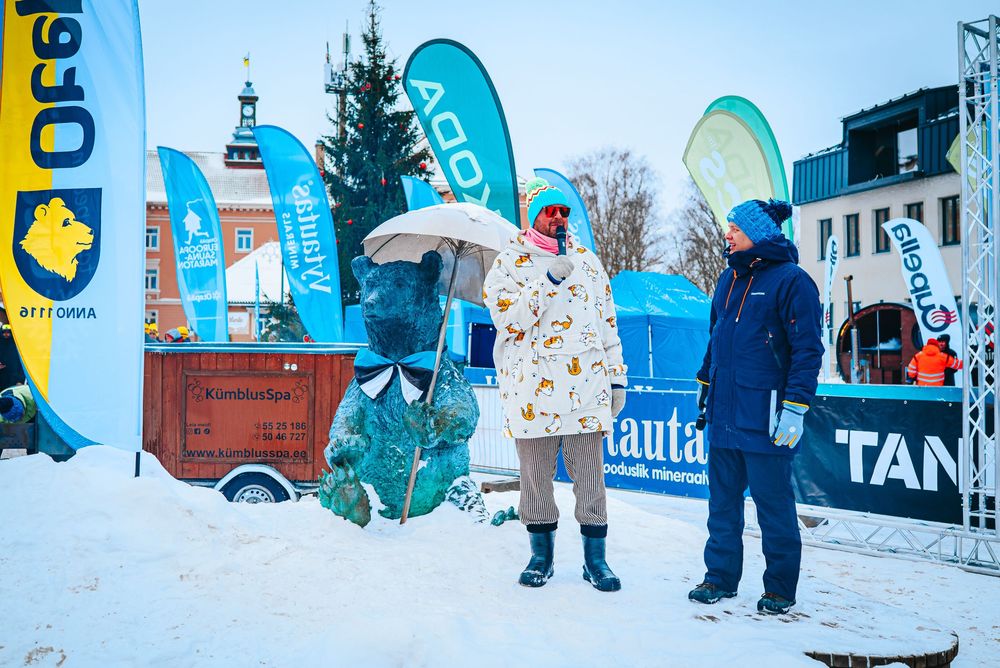 Winter sports event setup with blue promotional banners and flags in snowy outdoor setting.