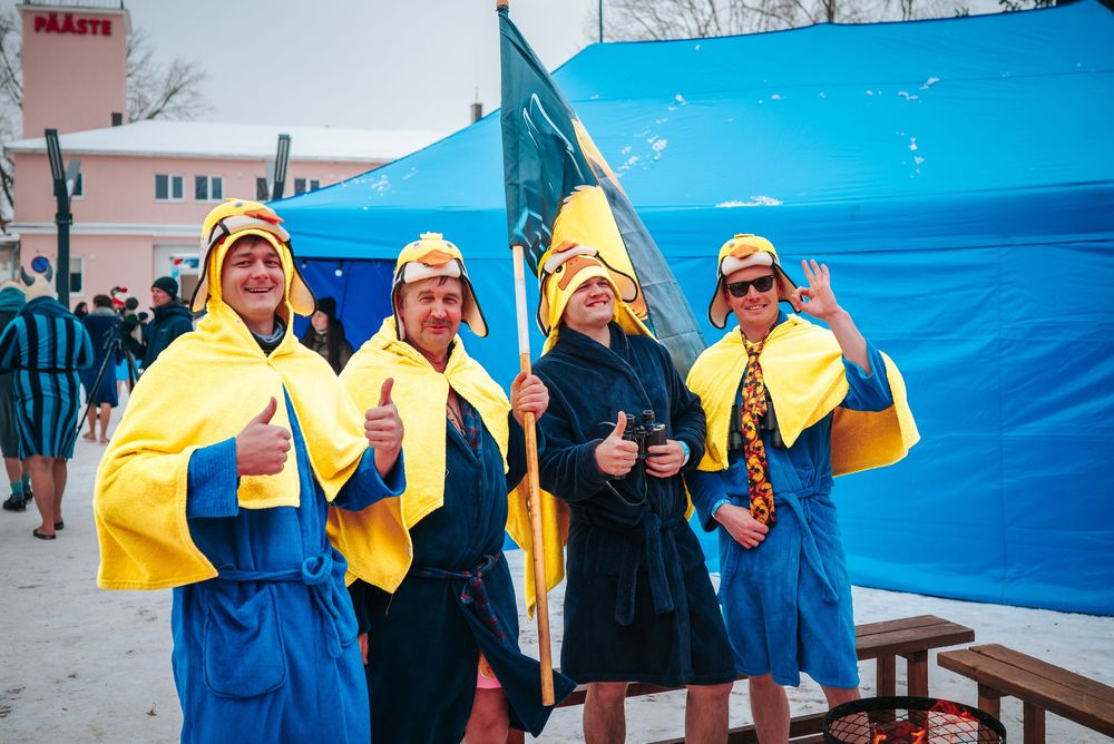 People in yellow rain gear stand in a line on a dock with blue tarps visible in the background.