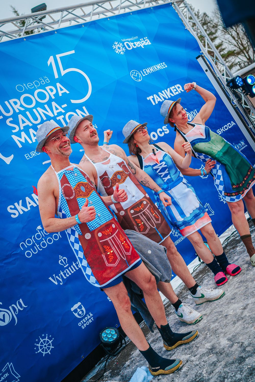Athletes drink water from bottles during an outdoor sports event with blue banners in the background.