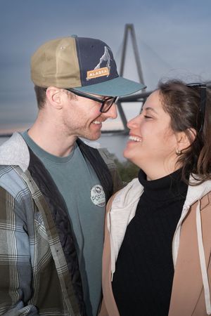 A sweet moment captured between a couple with a large suspension bridge in the background.