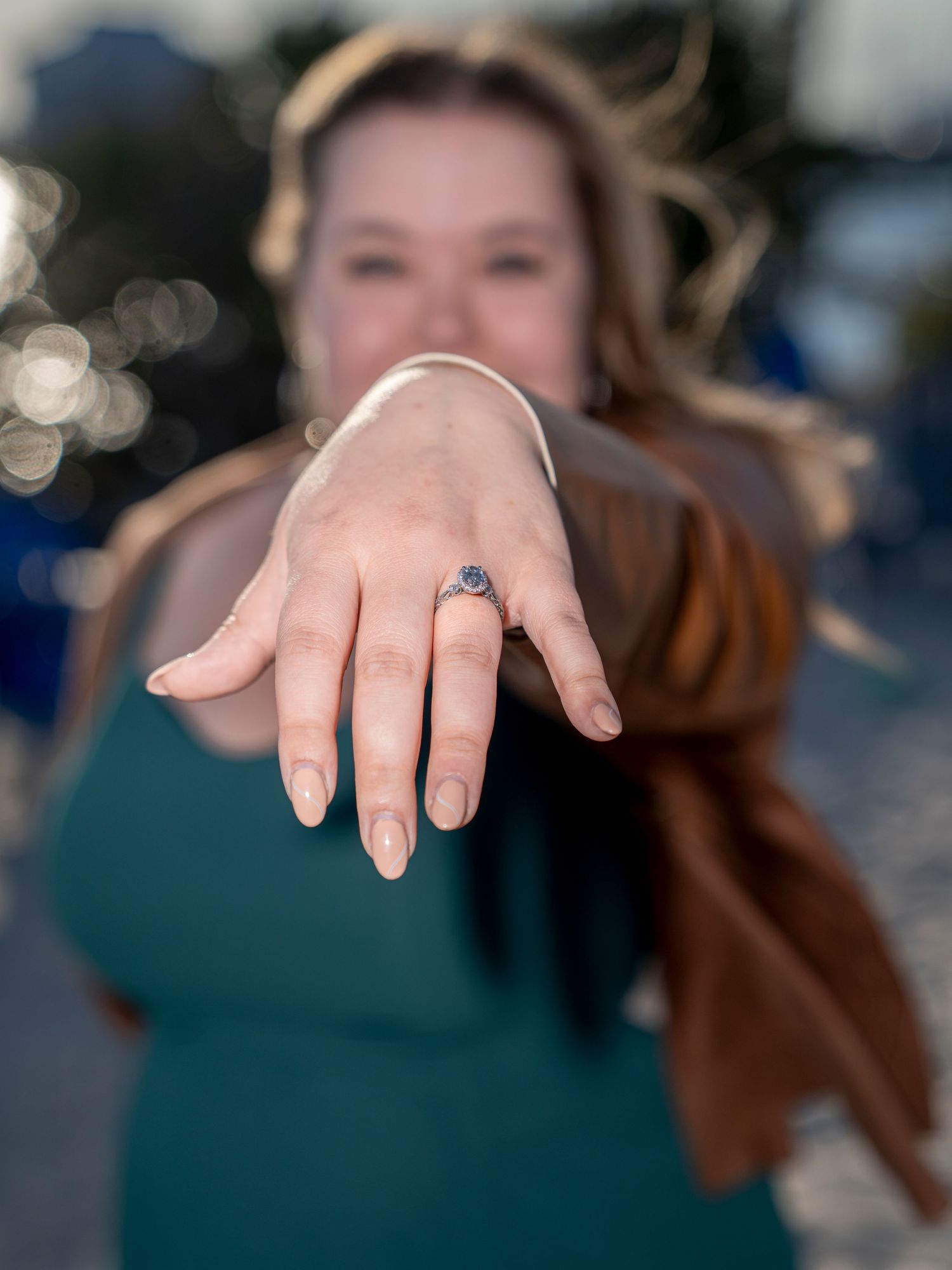 Close-up shots of an engagement ring with a blue gemstone on a woman's hand against a blurred background.