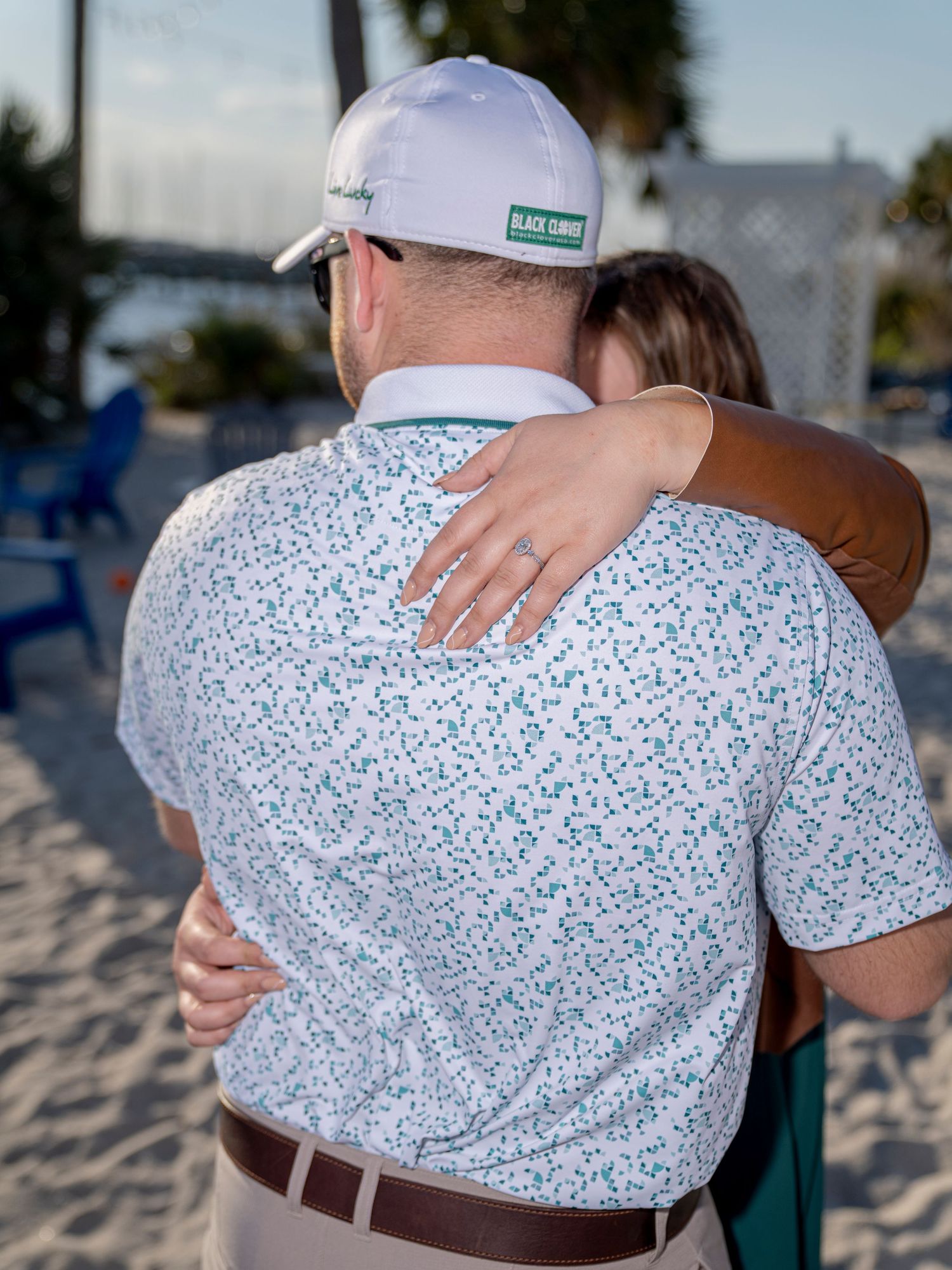 A series of photos showing a close embrace between two people wearing a white floral print shirt on a beach.