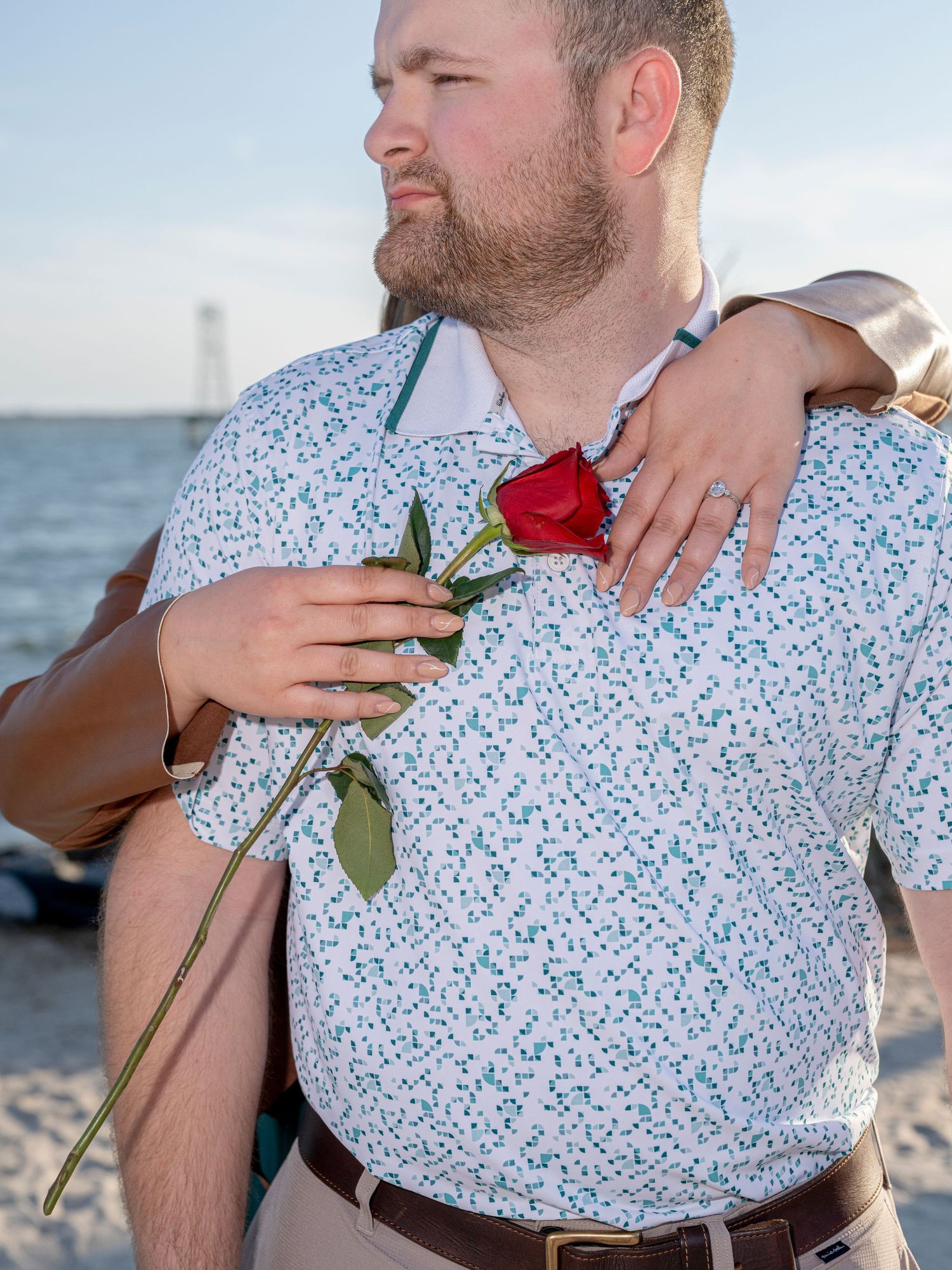 Series of photos showing a couple embracing on a beach wearing white and red floral attire.