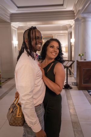 Couple dancing together in a bright hallway with marble floors and ornate decor.
