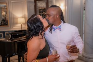 A romantic couple shares a kiss at an elegant venue with a grand piano and mood lighting in the background.