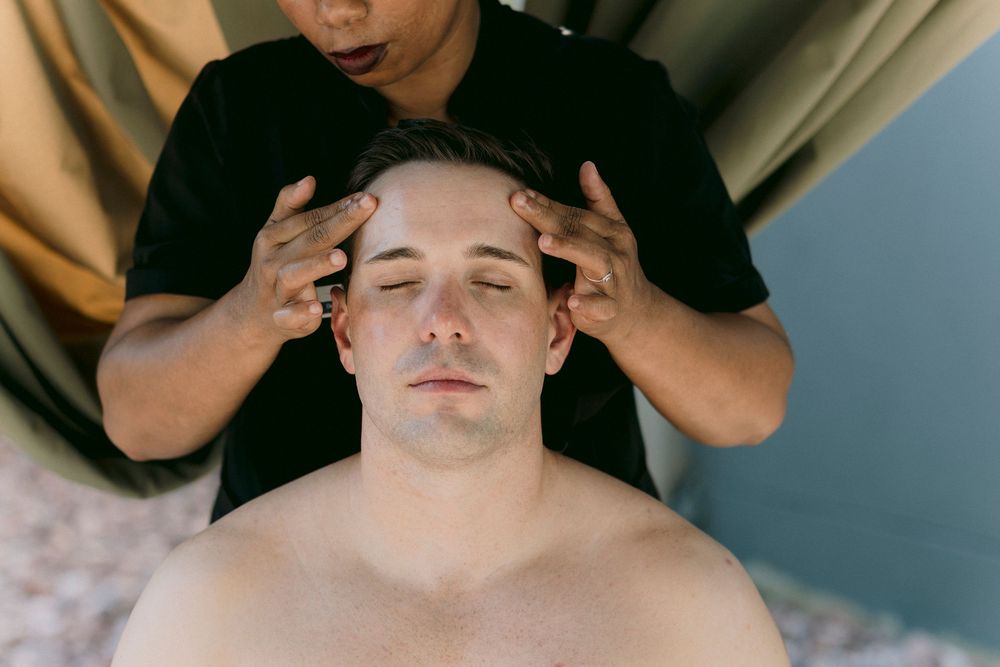 Therapist performing a relaxing head massage on a male client at a luxury spa.
