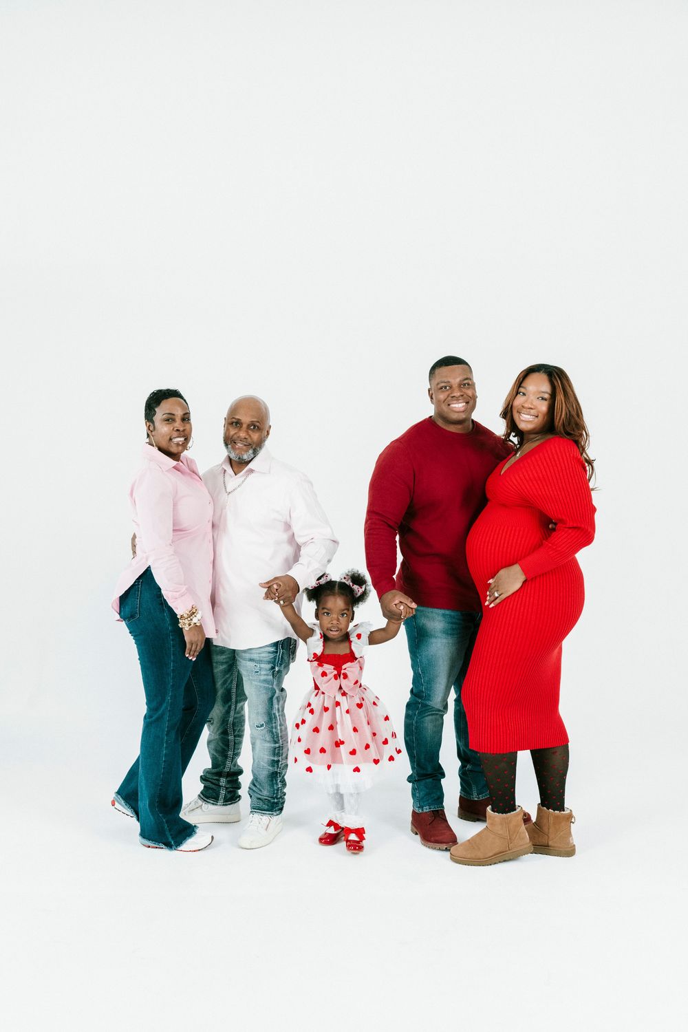 A family in coordinated red and white outfits poses together against a white background in three similar poses.