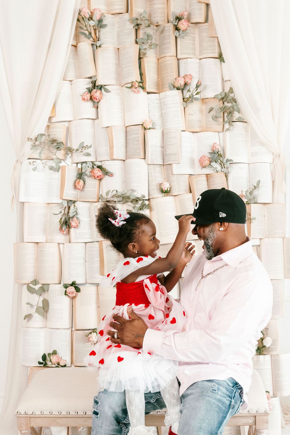 A parent and child play together against a backdrop of paper decorations and floral accents.