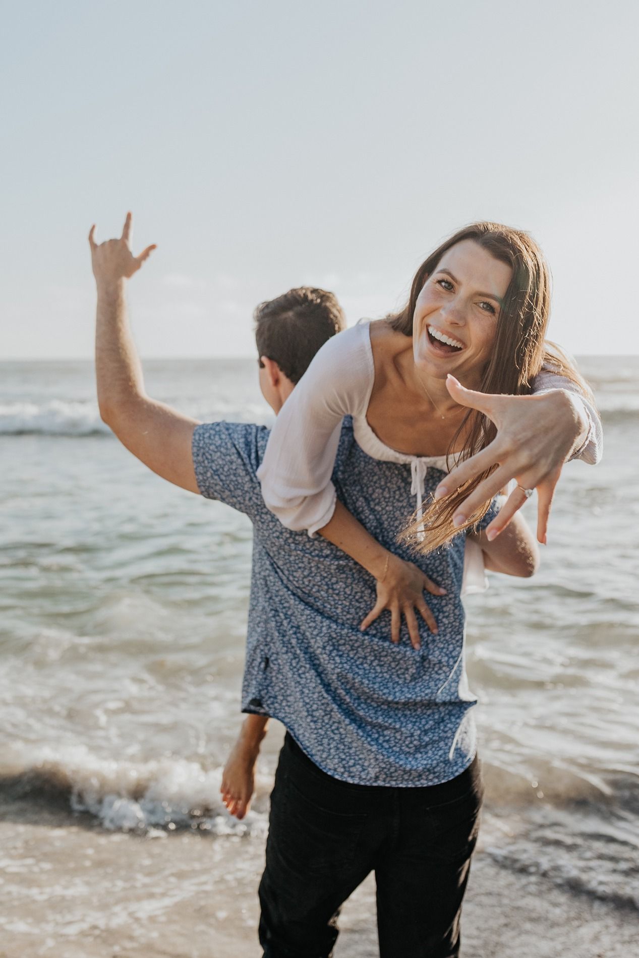 Joyful couple playing and laughing together on a beach at sunset with ocean waves in the background at Windansea Beach.