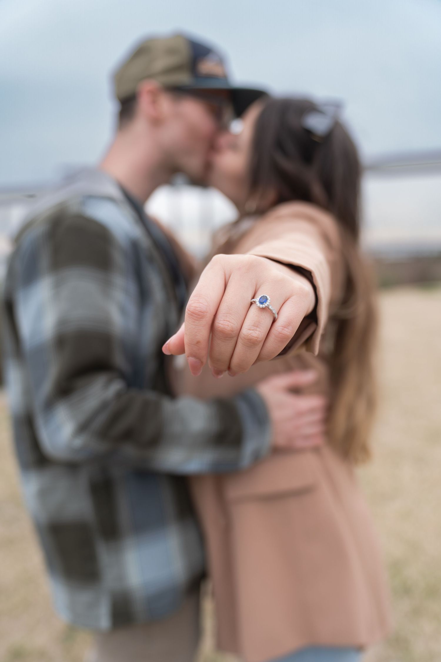 A couple embraces while showing off a new engagement ring in a series of romantic outdoor photos.