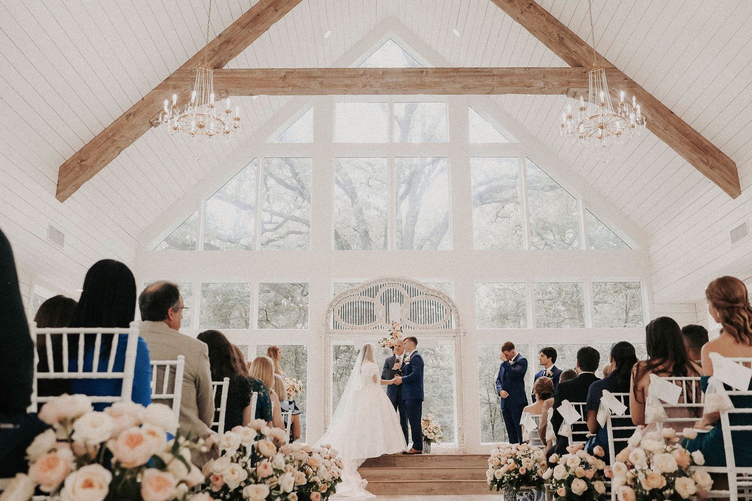 Bride and groom saying vows under floral ceremony arch at North Texas wedding venue